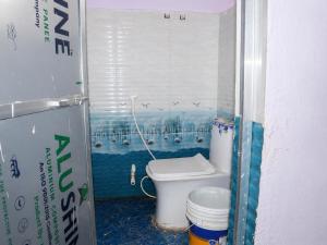 a bathroom with a toilet with a painting on the wall at Harshvardhan Lodge in Narsimhapur
