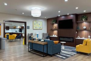 a living room with a blue couch and yellow chairs at Comfort Inn & Suites Concord - Kannapolis in Concord