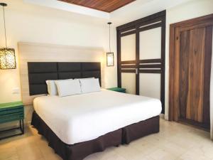 a bedroom with a large white bed and a wooden door at Hotel Faranda Guayacanes, a member of Radisson Individuals in Chitré