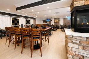 a restaurant with a bar with chairs and a fireplace at Maritime Inn Port Hawkesbury in Port Hawkesbury