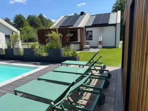 a group of lounge chairs next to a swimming pool at Leśna Polana Domki in Okuninka
