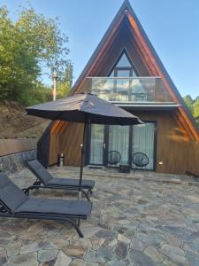a house with two lounge chairs and an umbrella at Panoramic Nicolas in Borsa