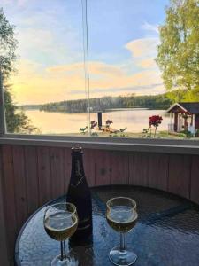 two glasses of wine on a table in front of a window at Idyllic cottage with lake view with 11 beds in Ludvika