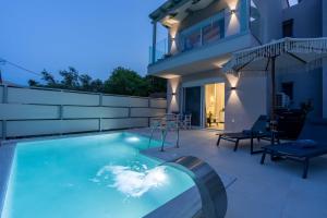 a swimming pool in front of a house at Aurea Ionian Villas in Apolpaina