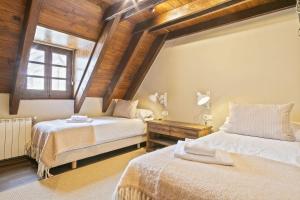 two beds in a room with wooden ceilings at Luderna - Casa con terraza Cuylas in Baqueira-Beret