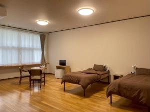 a bedroom with two beds and a table and a desk at あらとんとんの宿 in Setouchi