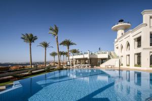 a swimming pool next to a building with a control tower at Sunrise Remal Beach Resort in Sharm El Sheikh