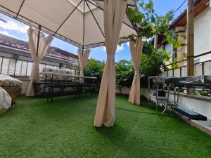 a patio with an umbrella and green grass at Apartamentos Ca' tio Celso in San Esteban de la Sierra