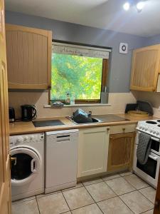 a kitchen with a washing machine and a window at The Wicket Cottage in Burlescombe +15 photos