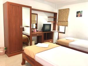 a bedroom with two beds and a desk with a television at เก็บตะวัน รีสอร์ท in Ban Hua Khao Sammuk