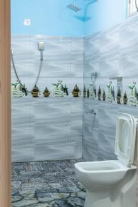 a bathroom with a toilet and some figurines on a wall at Rainforest Soul Villa in Mederipitiya
