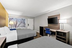 a hotel room with two beds and a desk and a tv at Quality Inn near Blue Spring in Orange City +35 photos