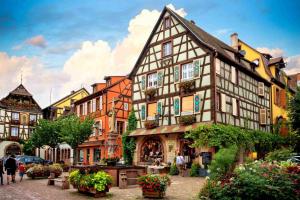 a building in a town with people walking around it at Lodge de la WEISS in Lapoutroie