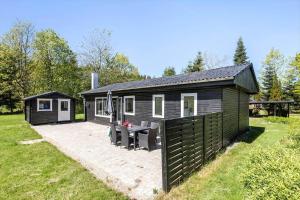 a black cabin with a patio and a table at 8804-Glesborg-Vesttoften-20 in Glesborg