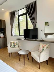 a living room with two chairs and a flat screen tv at Mimosa Forest Hotel Villa in Xuan An