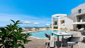 a swimming pool with a table and chairs next to a building at Bella Vista Hotel "by Checkin" in Hersonissos