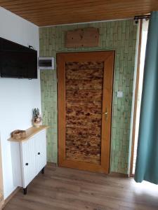 a wooden door in a room with green tiles at Sóz-Lak in Mezőcsát
