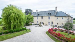 an exterior view of a large stone house with flowers at La Ferme de la Gronde in Magny-en-Bessin
