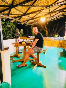a man sitting on a chair at a table at Mango Tree House Yala Safari Hotel in Tissamaharama