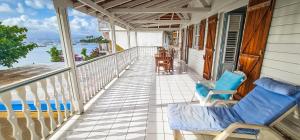 a balcony with chairs and tables on a house at Villa bougainvillier in Les Trois-Îlets