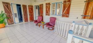 a porch with two pink chairs and a table at Villa bougainvillier in Les Trois-Îlets