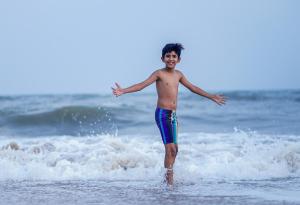 a young man is standing in the ocean at Shelter Beach Resort in Mahabalipuram +115 photos