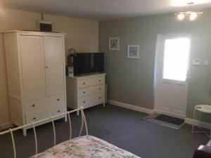 a bedroom with a bed and a dresser with a television at Fishermans Rest in Newport