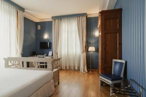 a bedroom with a bed and a desk and a chair at Hotel Palazzo Guiscardo Pietrasanta in Pietrasanta