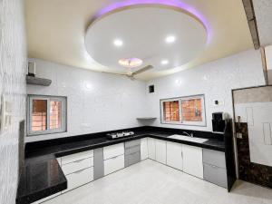 a kitchen with black and white counters and a ceiling at Ansh Bunglow in Belgaum