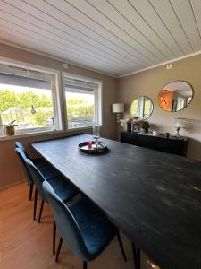 a dining room with a large black table and chairs at Enebolig i Larkollen in Moss