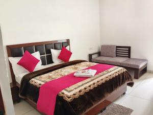 a bedroom with a bed with pink pillows and a chair at Hotel Shri Mahavir in Chamoli