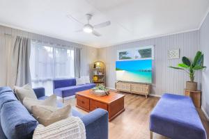 a living room with blue couches and a tv at The Hideaway in Bargara