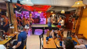 a group of people sitting at tables in a room with a pool table at Blanco Central in Phi Phi Islands