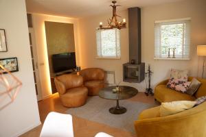 a living room with a couch and chairs and a table at De Noteboom 6-persoons, verwarmd privé zwembad, hottub, overdekte lounge met haard, panorama sauna, sunshower, luxe, wifi in Lievelde