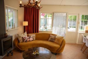 a living room with a couch and a table at De Noteboom 6-persoons, verwarmd privé zwembad, hottub, overdekte lounge met haard, panorama sauna, sunshower, luxe, wifi in Lievelde