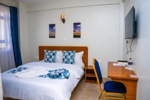 a bedroom with a bed and a desk with a computer at Sai Inn Eldoret in Eldoret