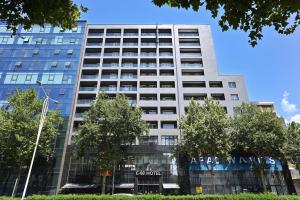 ein hohes weißes Gebäude mit Bäumen davor in der Unterkunft E-88 Hotel in Tirana