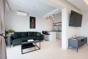 a living room with a green couch and a kitchen at Villa LUX 55 in Tučepi