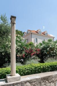a pillar in front of a house with flowers at The Old Town Hostel-Villa Gradac in Dubrovnik