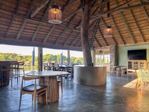 a restaurant with tables and chairs and windows at Tzamenkomst River Lodge in Colesberg