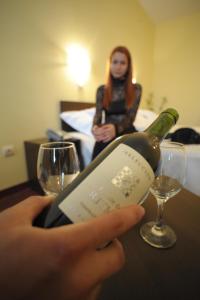 ソフィアにあるHotel Alexanderの女がワインをテーブルの上に持っている