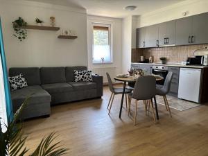 a living room with a couch and a table and chairs at Six Apartman in Bükfürdő