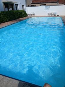 a large blue swimming pool with two benches in it at Duplex met zwembad Neoportus in Nieuwpoort