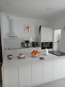a white kitchen with a bowl of oranges on a counter at Beau séjour in Pedreguer