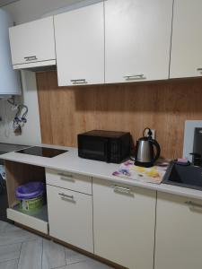 a kitchen with white cabinets and a microwave at Zarvanska str apartment in Kamianets-Podilskyi