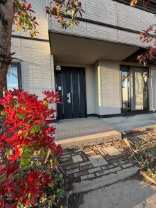 a building with a black door and red flowers at ENZAN STAYS Yamanashi in Enzan