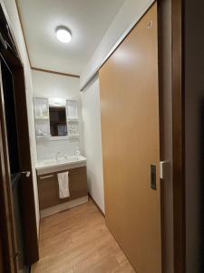 a bathroom with a door and a sink and a mirror at ENZAN STAYS Yamanashi in Enzan