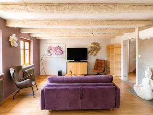 a living room with a purple couch and a tv at Le Plébiscité Maison Premium sur la Route des Vins d'Alsace in Marlenheim
