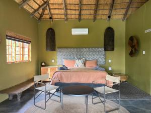 a bedroom with a bed with two chairs and a table at Tzamenkomst River Lodge in Colesberg