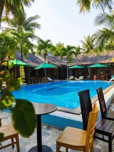 a large swimming pool with chairs and a table at OXY Cave Homestay Mũi Né in Mui Ne